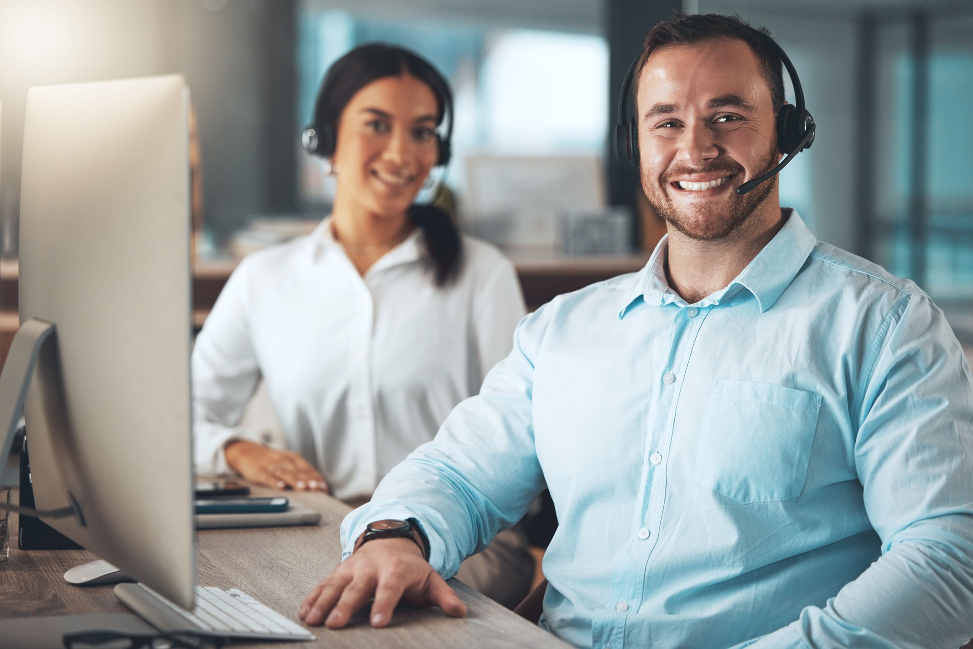Shot of two young call centre agents sitting together in the office and using a computer