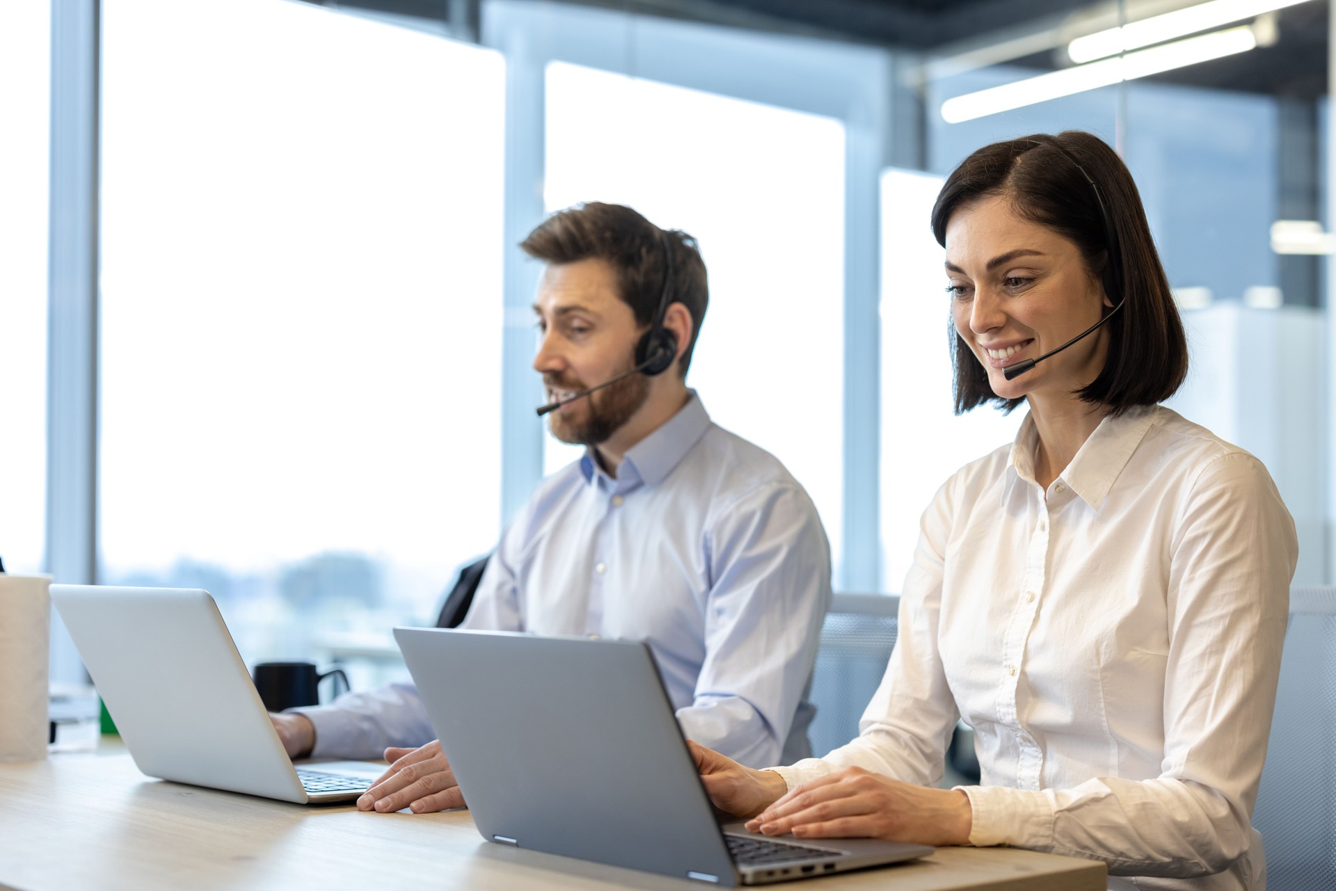 Call center professionals in office using headsets and laptops while engaging with clients for customer support and communication
